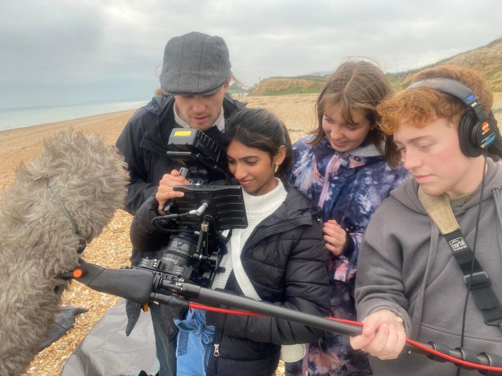 Image of young people on a beach with film equipment
